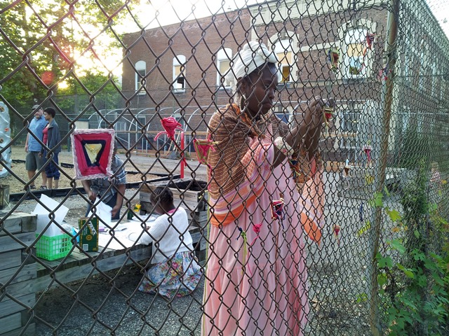 Weaving Protective Eyes, Ojo de Dios, into the Boggs School fence, August 2014, Detroit